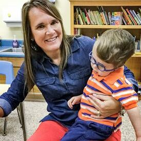 Trish Logan, Coordinator holding a small boy on her lap.